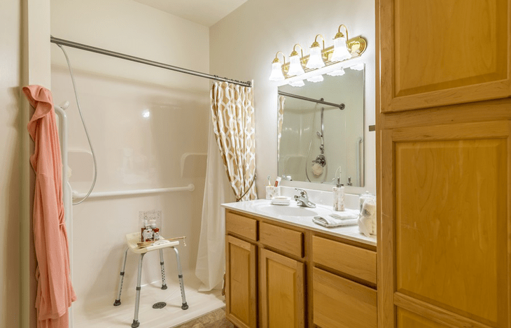 A well-lit bathroom featuring a shower with a curtain, double vanity, and wooden cabinets.