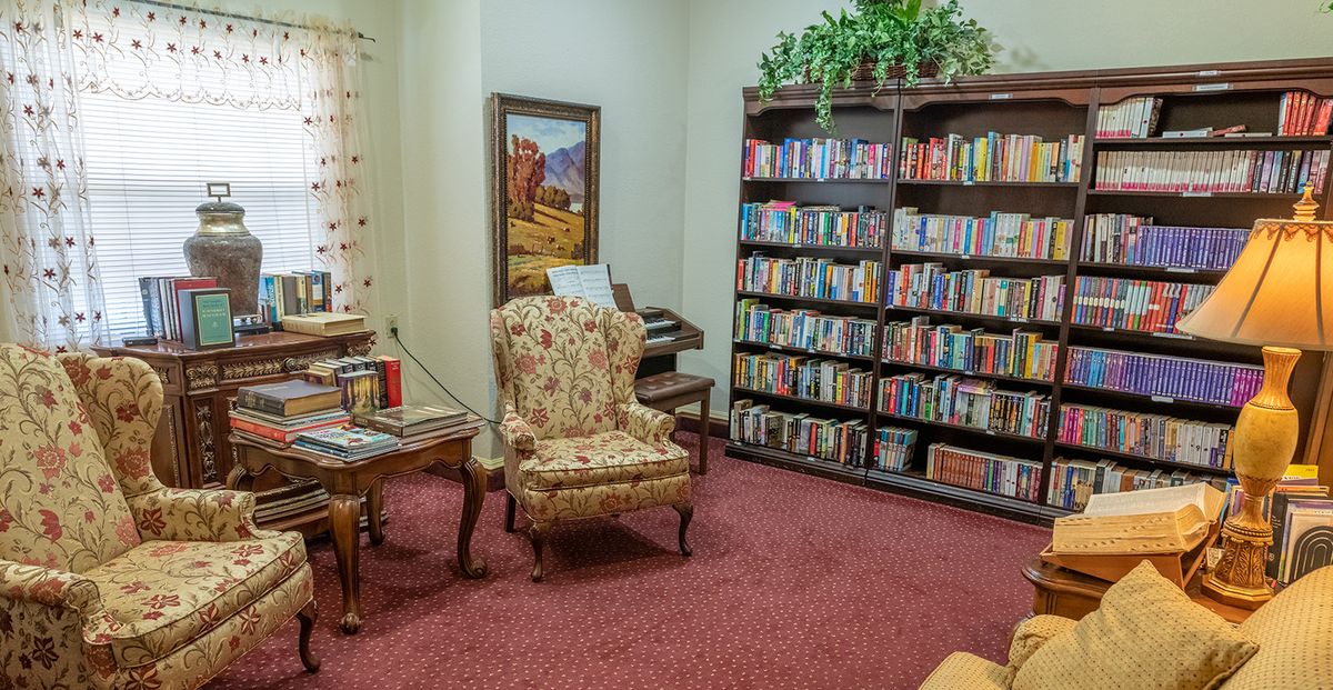 A cozy reading room with an armchair and a bookshelf filled with books.