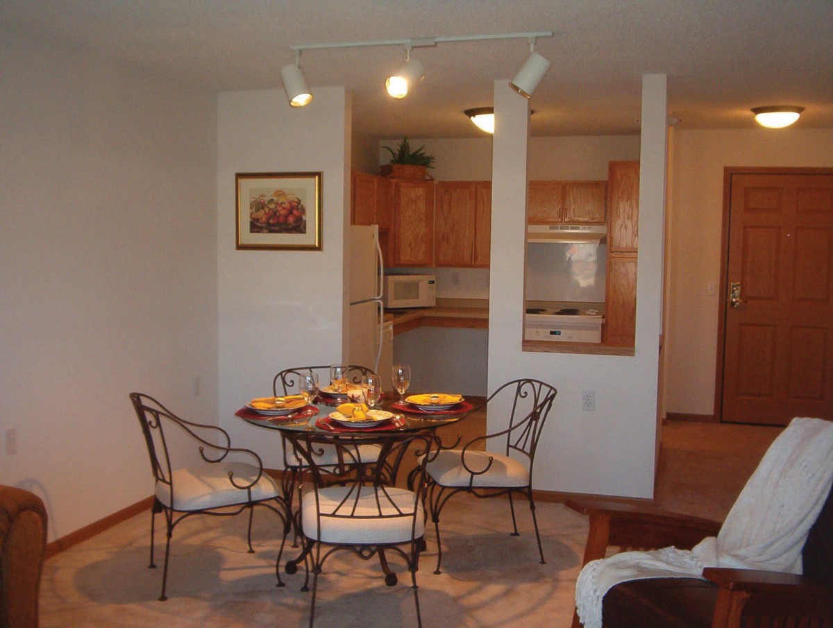 A cozy dining area with a round table and chairs, adjacent to a compact kitchen.