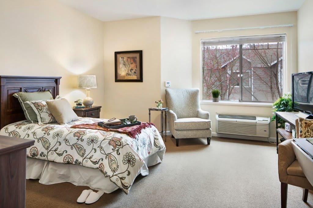 A cozy bedroom with elegant furnishings and a large window offering a view of the outdoors.