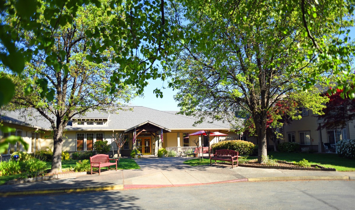 A charming building surrounded by trees and benches on a sunny day.