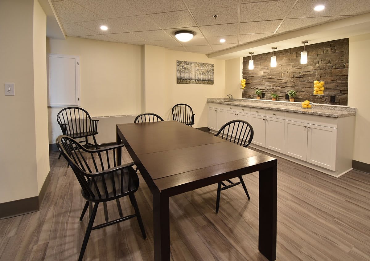 Modern dining area with a wooden table and chairs, featuring stylish lighting and kitchen space.