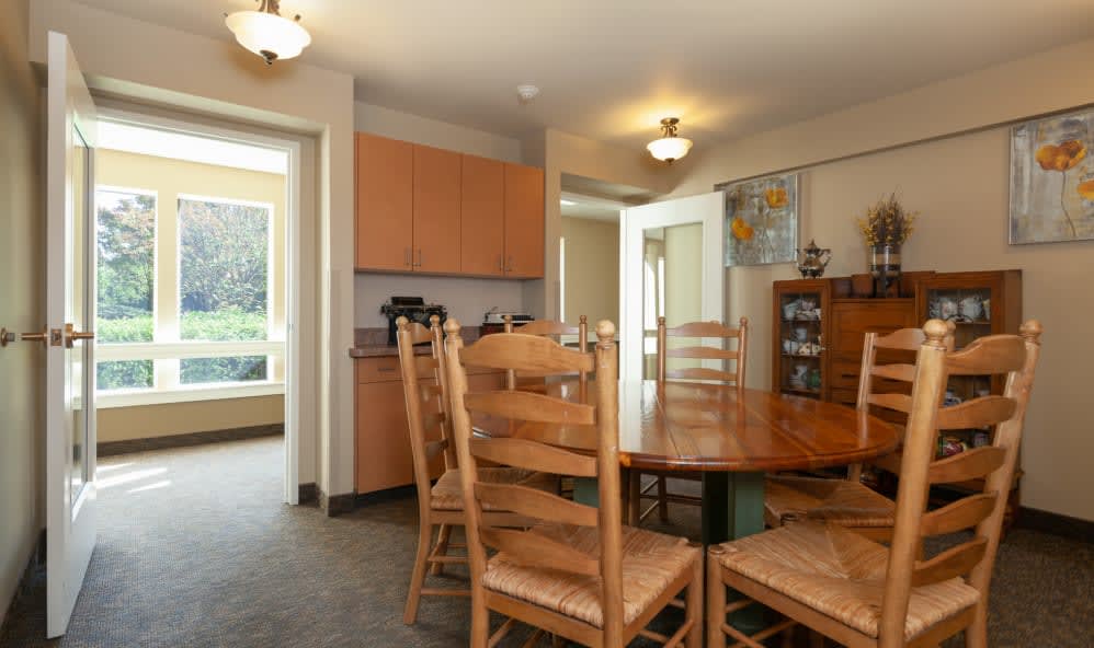 A cozy dining room with wooden furniture, adjacent to a kitchen area.