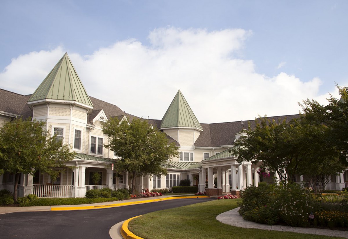 A picturesque building with green-roofed turrets surrounded by trees.
