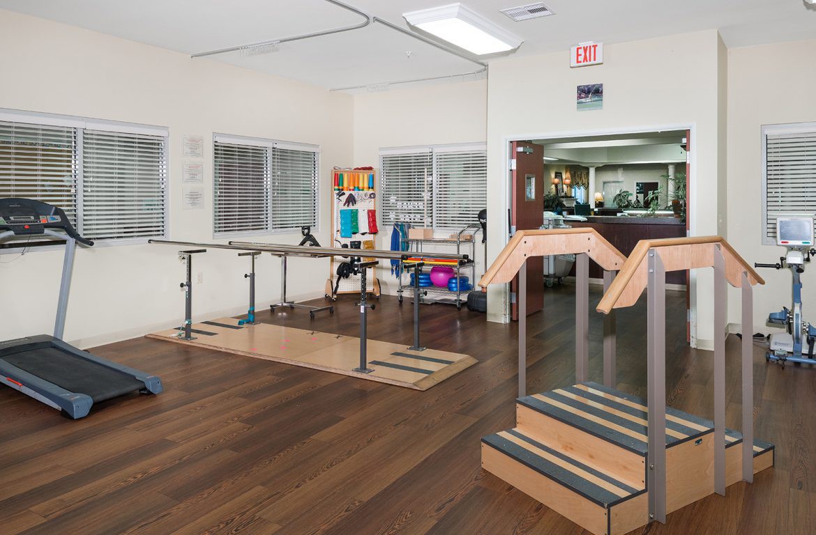 A rehabilitation clinic with exercise equipment and wooden floors.