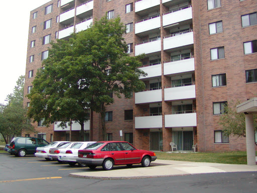A view of a multi-story apartment building with a parking lot in front.