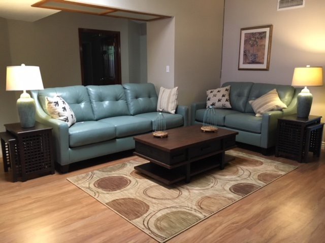 A cozy living room featuring two blue sofas, a wooden coffee table, and a patterned rug.