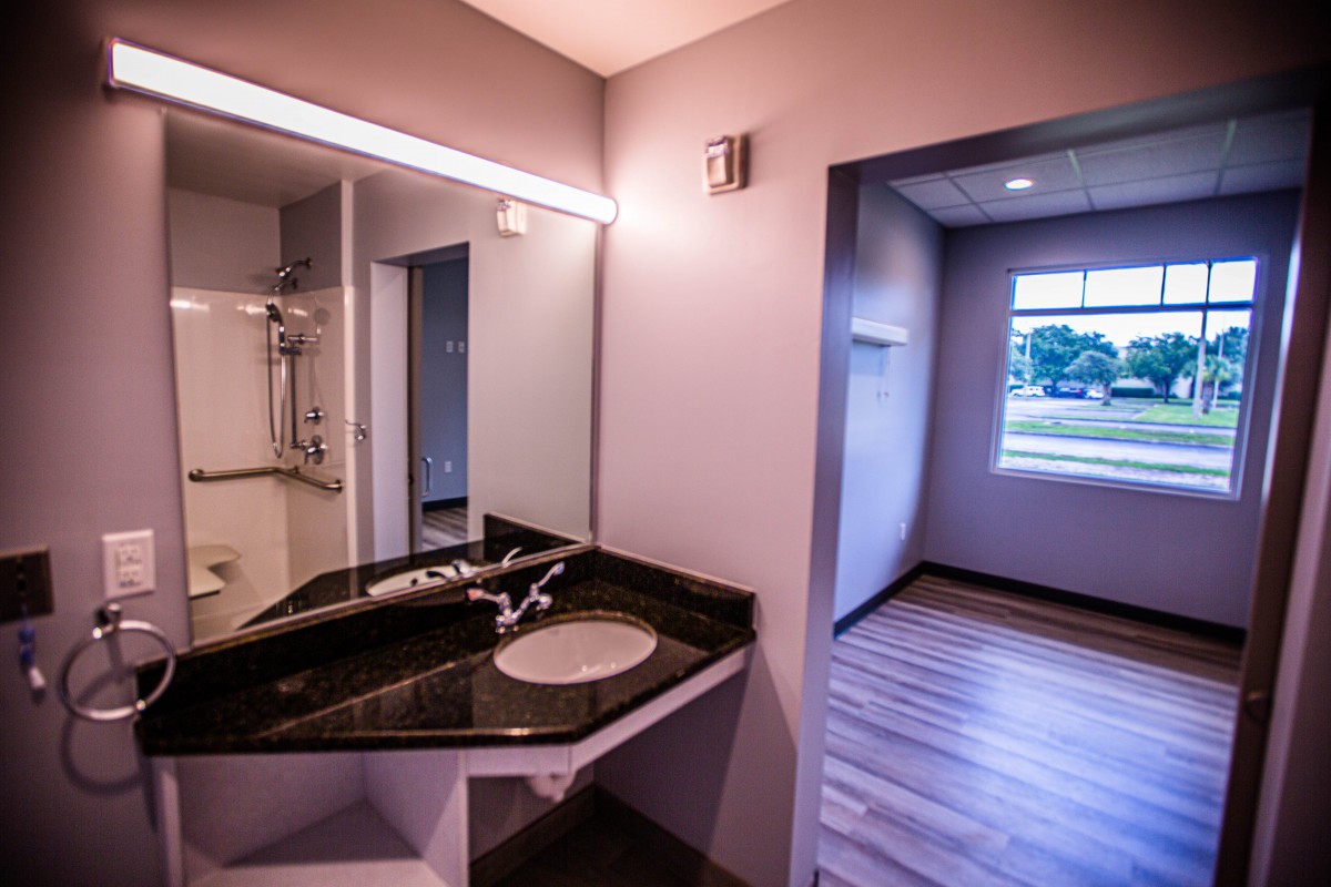 A modern bathroom interior with a sleek sink, mirror, and large window.