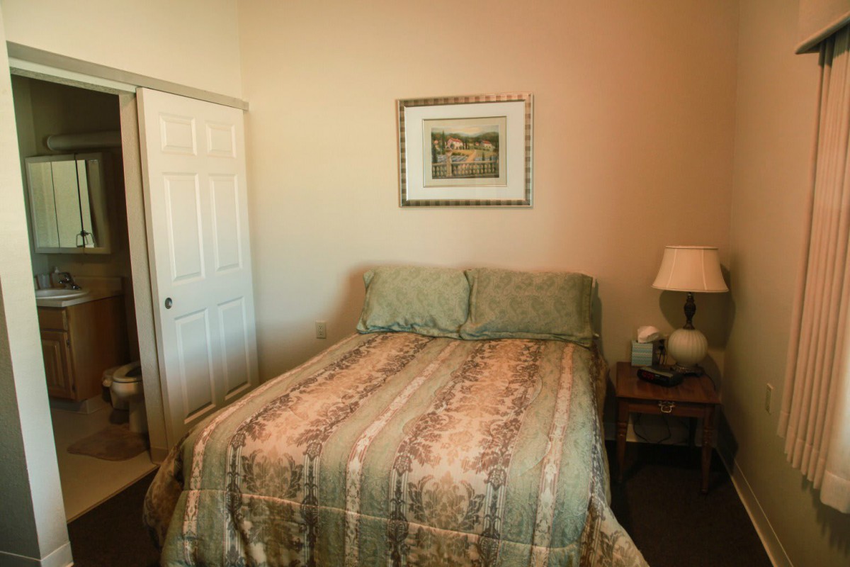 A cozy bedroom with a neatly made bed and a bedside lamp.