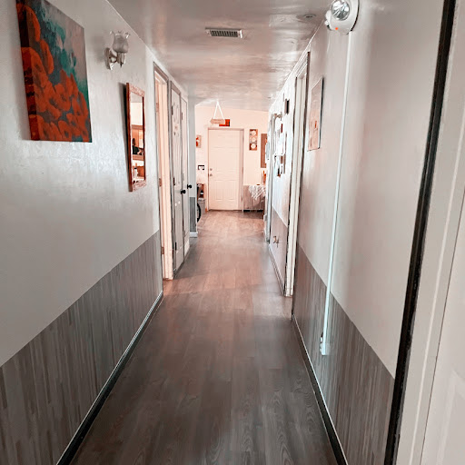 A well-lit interior hallway featuring artwork on the walls and a wooden floor.