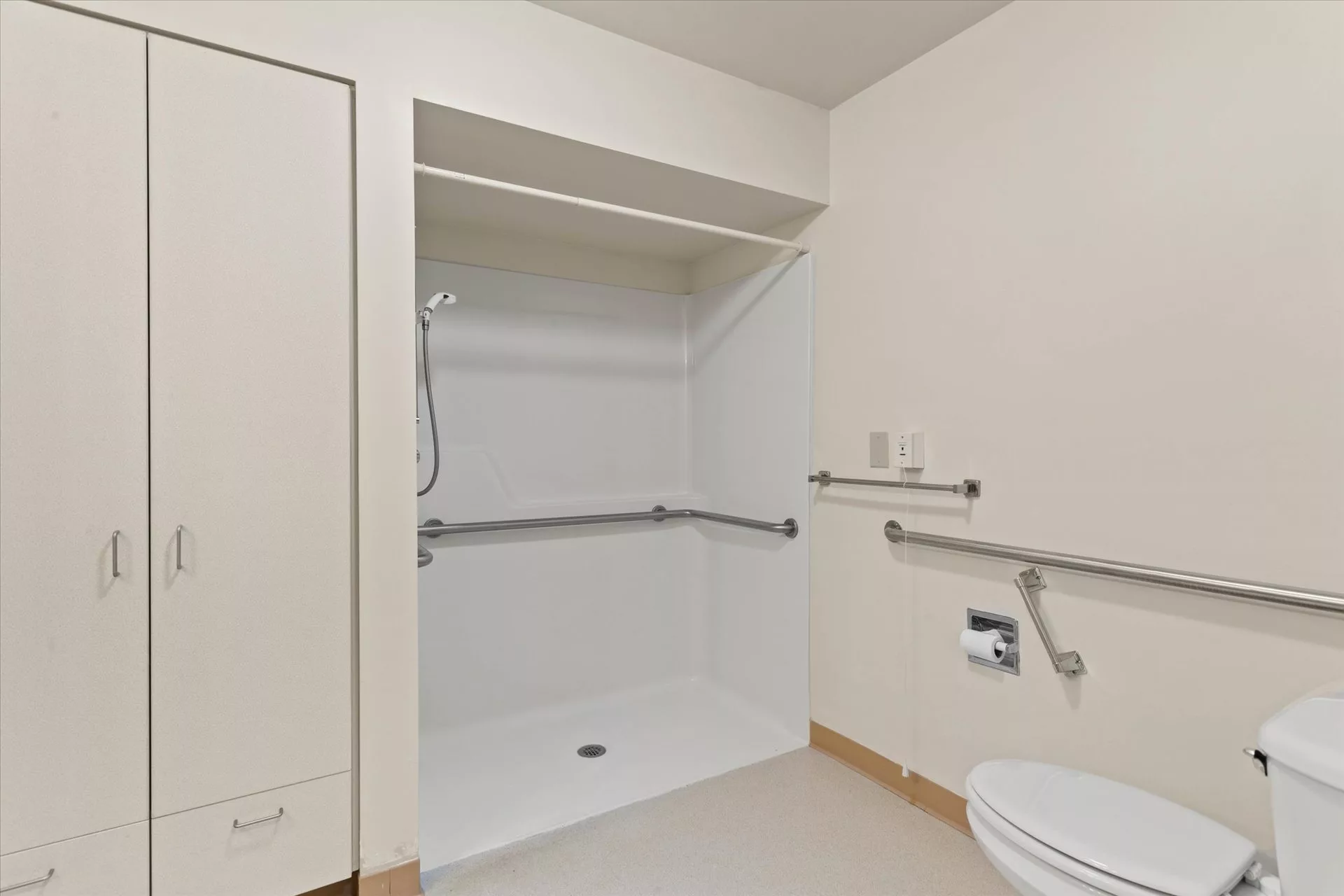A modern, accessible bathroom equipped with a roll-in shower and grab bars.