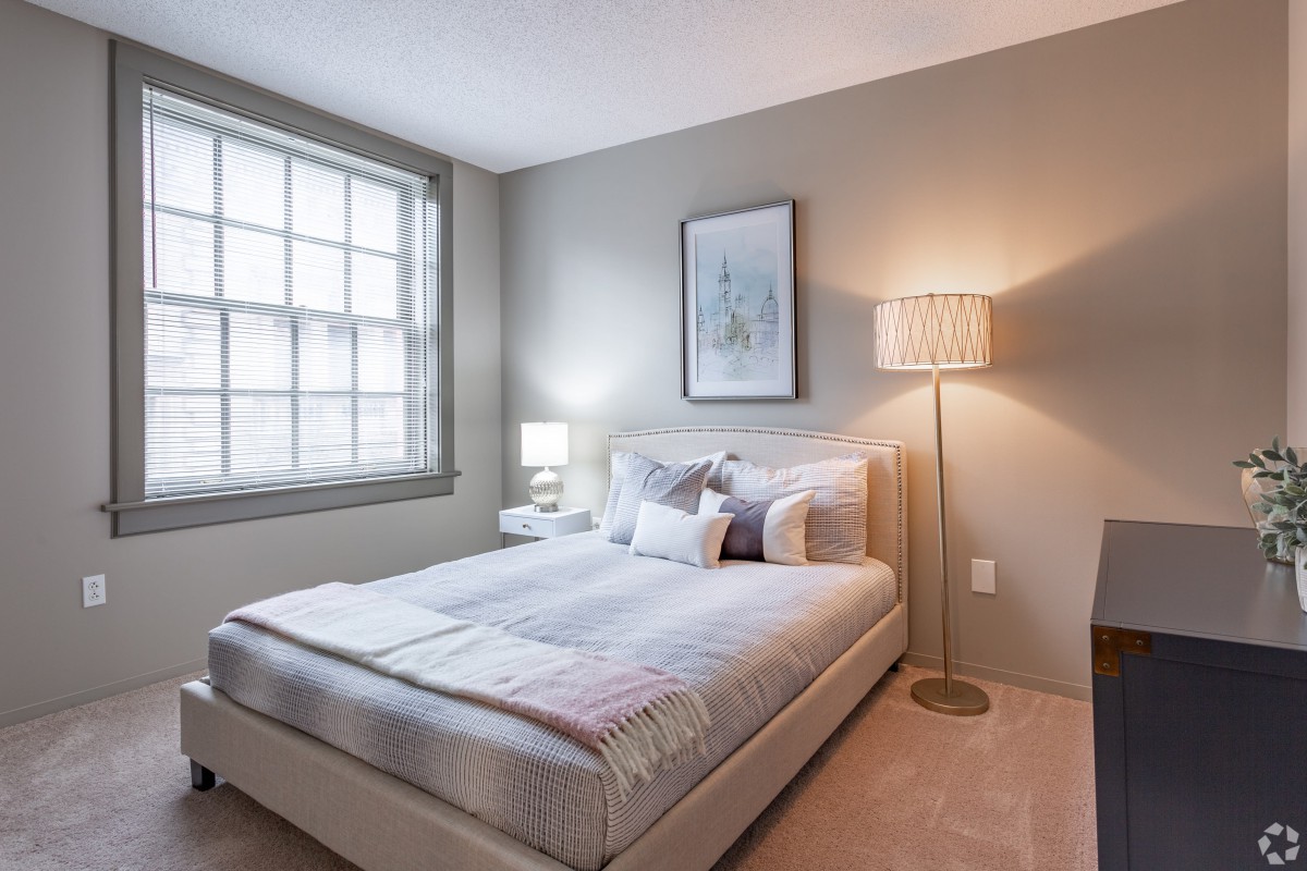 A cozy, modern bedroom with minimalist decor featuring a comfortable bed, bedside lamps, and a large window.