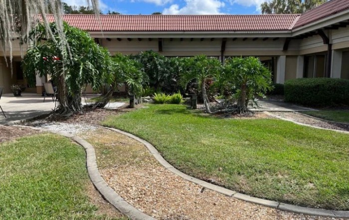 A landscaped garden with a curved gravel pathway leading to a house, surrounded by lush greenery.