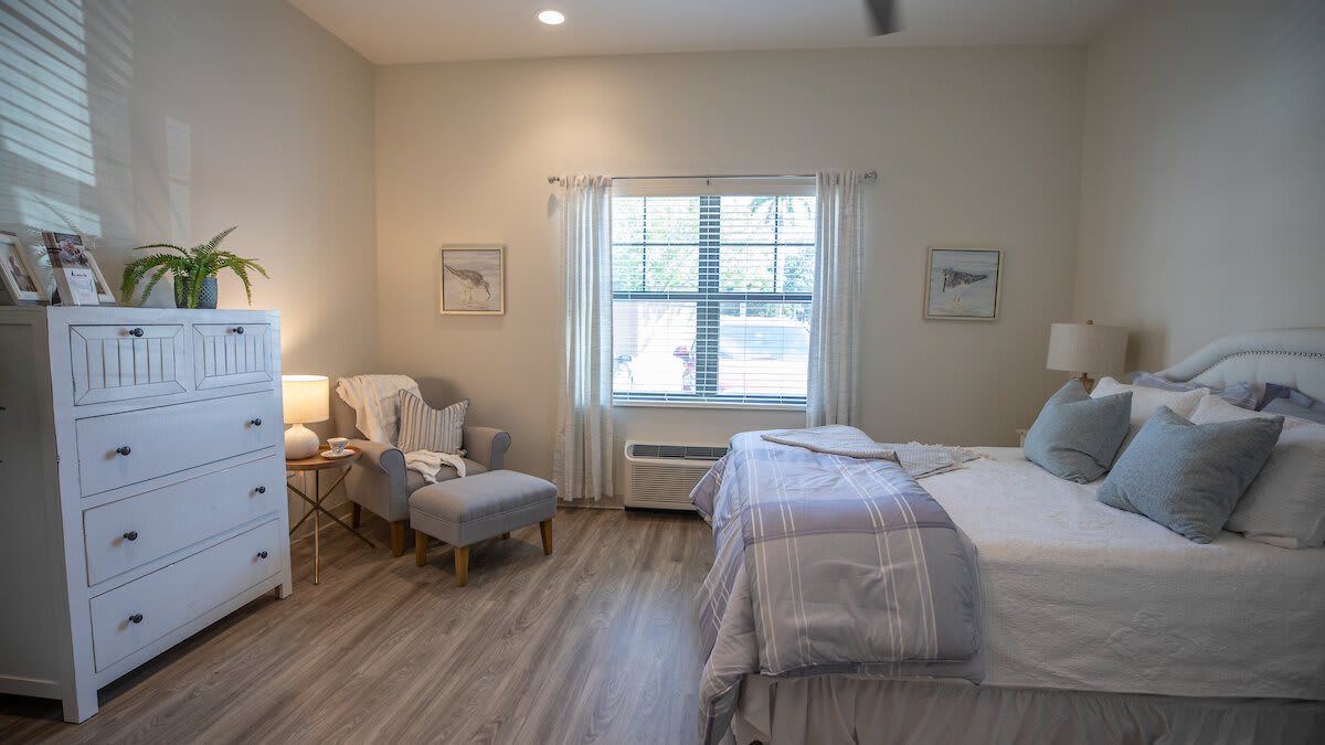 A cozy bedroom with a double bed, a comfortable chair, and soft lighting.