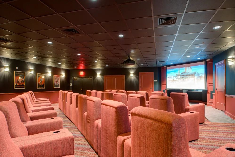 A cozy theater with plush red seating and a large screen at the front.