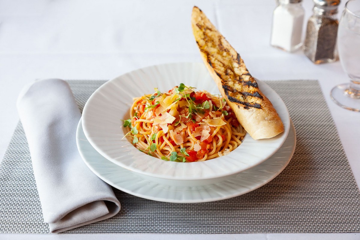 A delicious plate of spaghetti garnished with herbs and served with grilled bread.