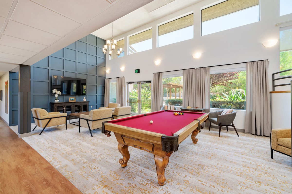 A spacious and modern living room featuring a billiards table and large windows allowing for abundant natural light.