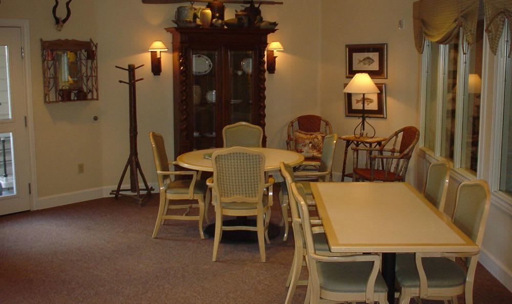 A cozy dining room with a circular table surrounded by chairs, a cabinet against the wall, and warm lighting from lamps.