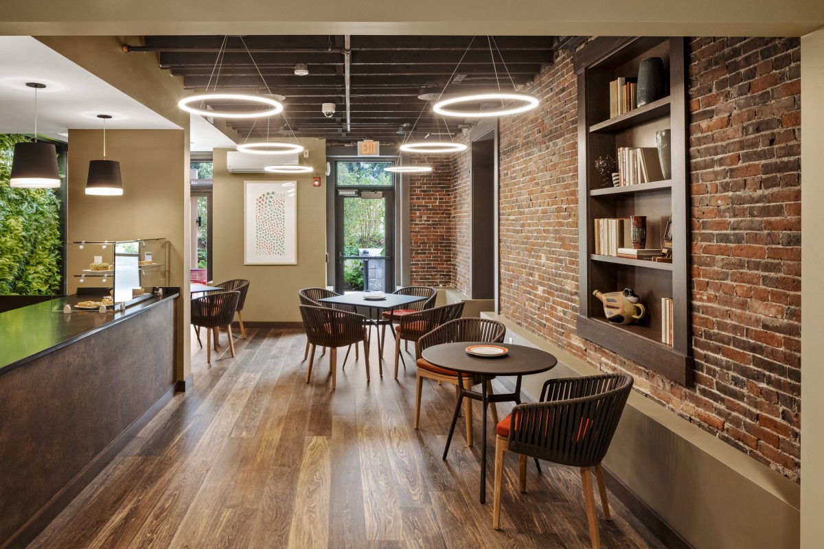 A modern cafe interior with brick walls, wooden flooring, and cozy lighting.