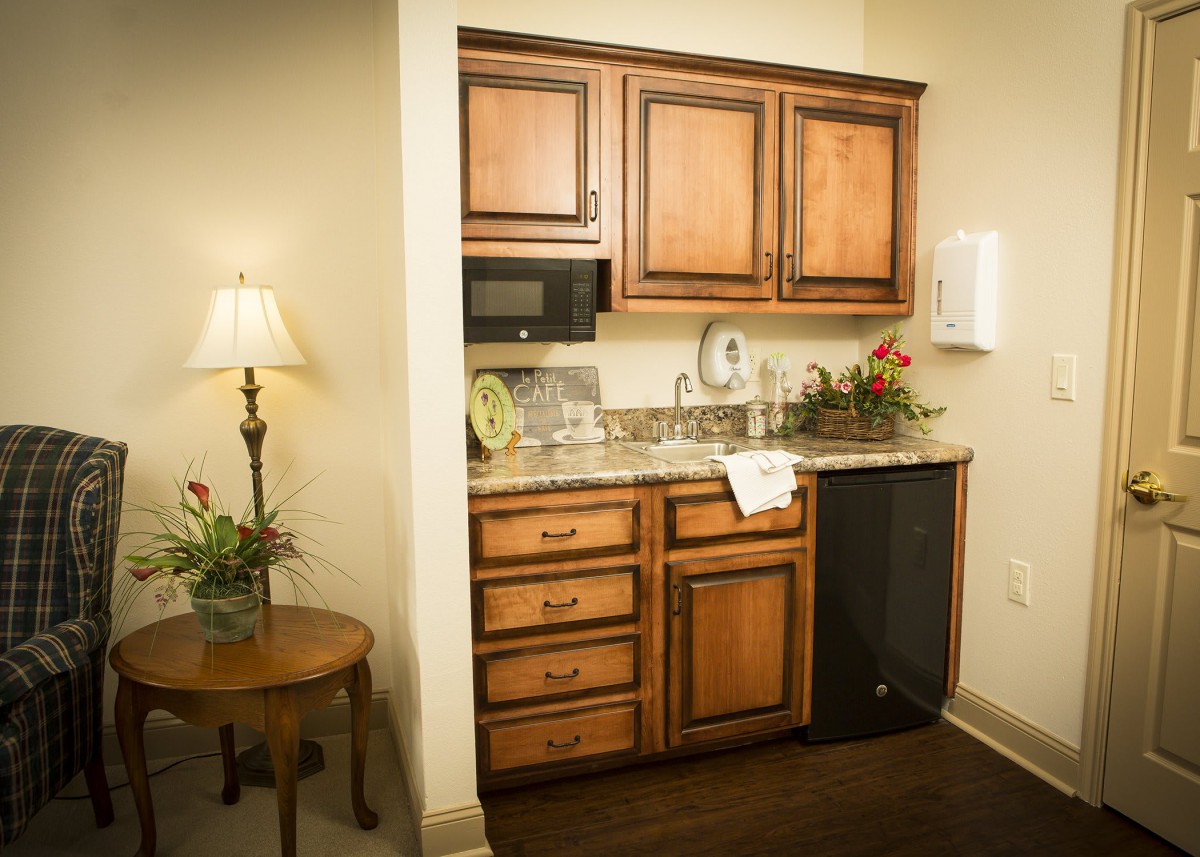 A compact kitchenette with wooden cabinetry and modern appliances.