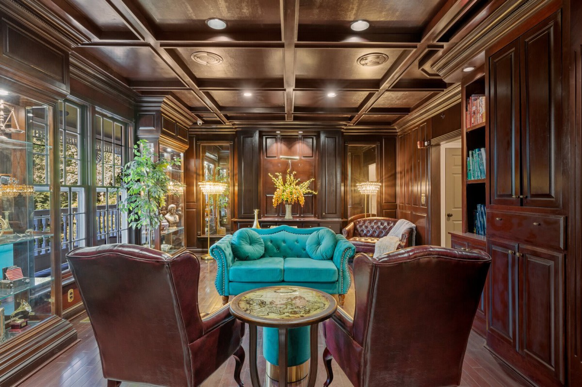 A luxurious living room with wood-paneled walls, elegant lighting, and plush furniture.