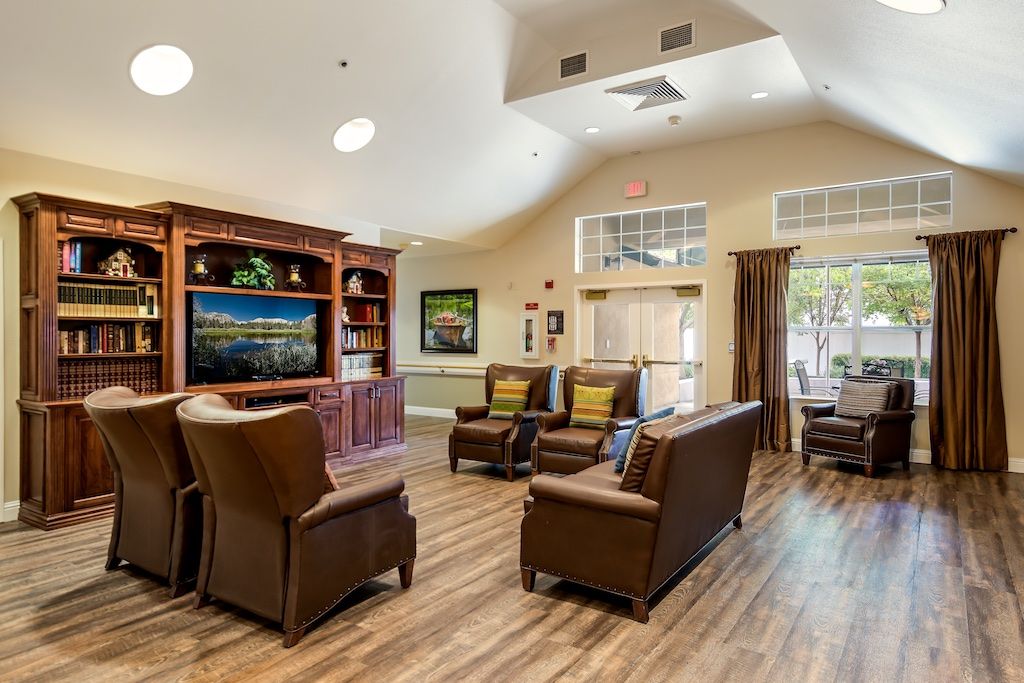 A cozy living room with leather seating, a television, and a bookshelf.