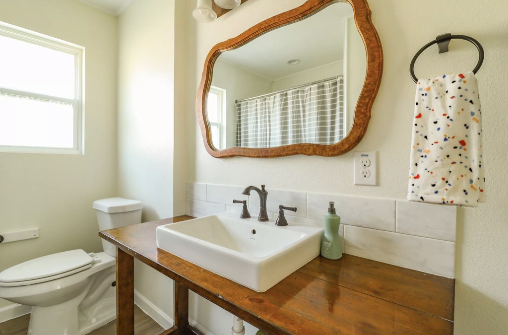 Rustic bathroom with wooden countertop and decorative mirror.