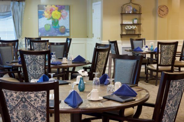 A cozy dining room setup with neatly arranged tables and blue napkins.