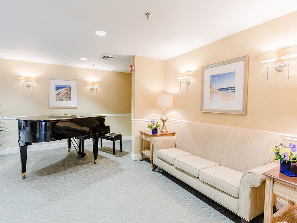 A cozy living room featuring a grand piano, a comfortable sofa, and elegant wall art.