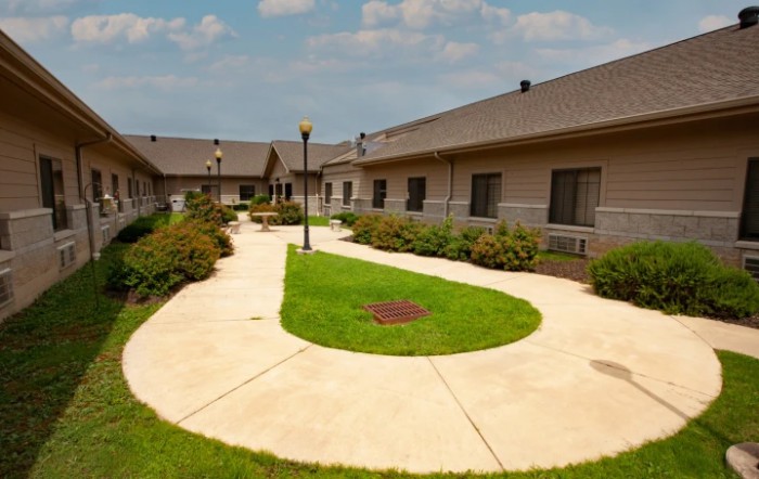 A well-maintained courtyard with pathways, grass, and surrounding buildings under a cloudy sky.