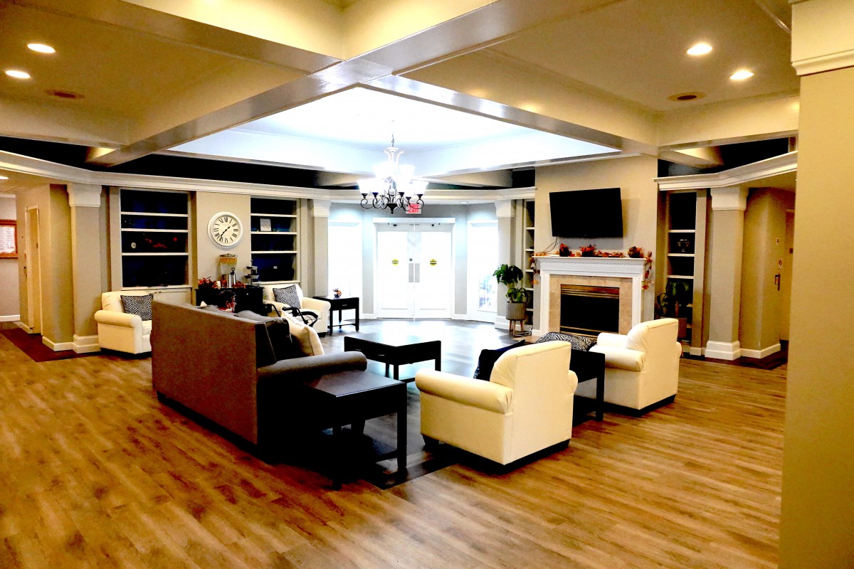 A modern living room with comfortable seating, a television above the fireplace, and elegant wood flooring.