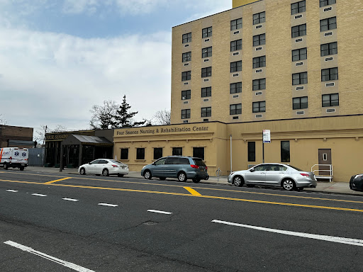 A view of a hospital building with parked cars in the foreground.