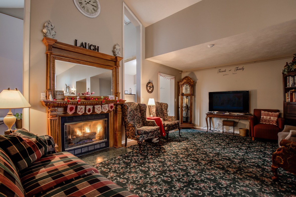 A warm and inviting traditional living room with a fireplace, armchairs, and decorative elements.