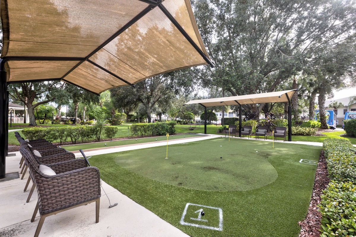 A relaxing outdoor patio with seating and shade canopies surrounded by greenery.