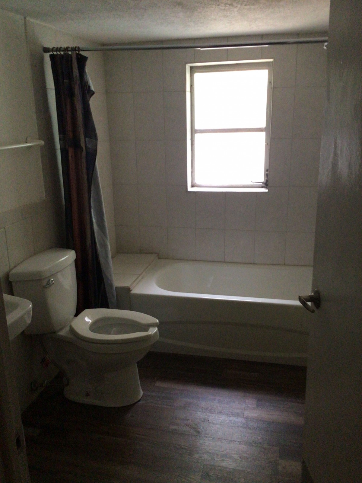 A bathroom with a toilet, bathtub, and window.
