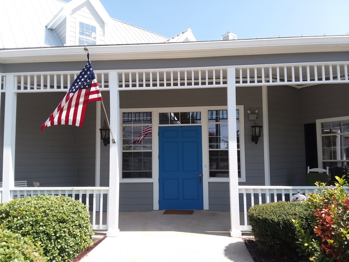 A charming house with a blue front door and an American flag on the porch.
