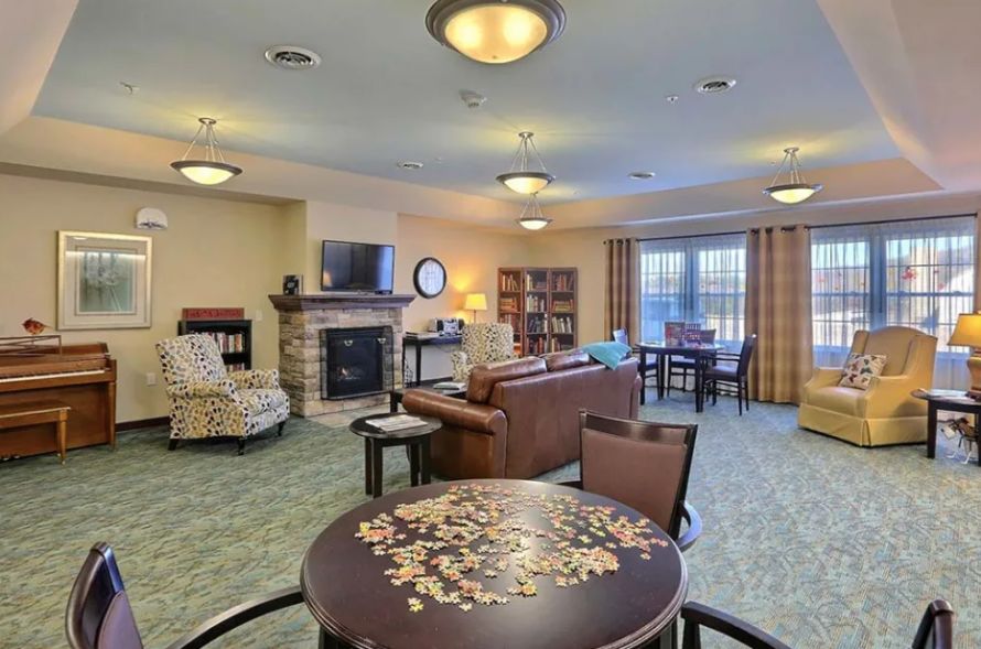 A cozy living room with a fireplace, comfortable seating, and bookshelves under warm lighting.
