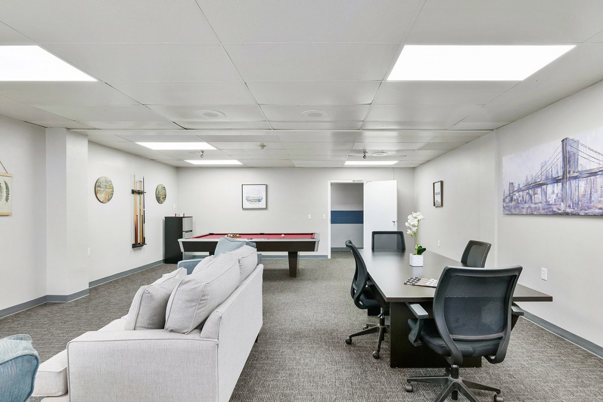 A modern office space featuring a conference table, sofa, and pool table.