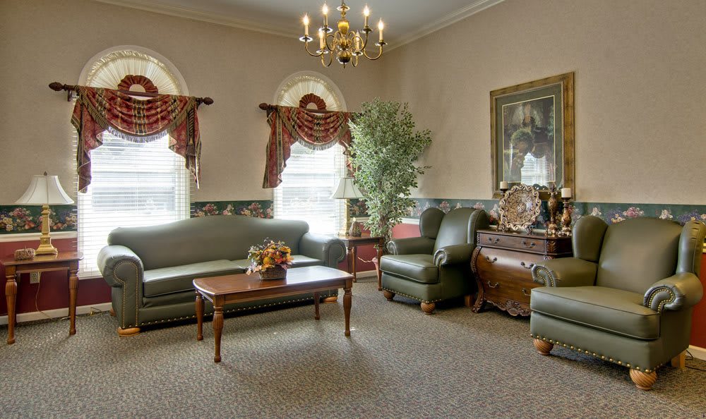 A traditionally styled living room featuring sofas, an armchair, a coffee table, and elegant curtains under a chandelier.