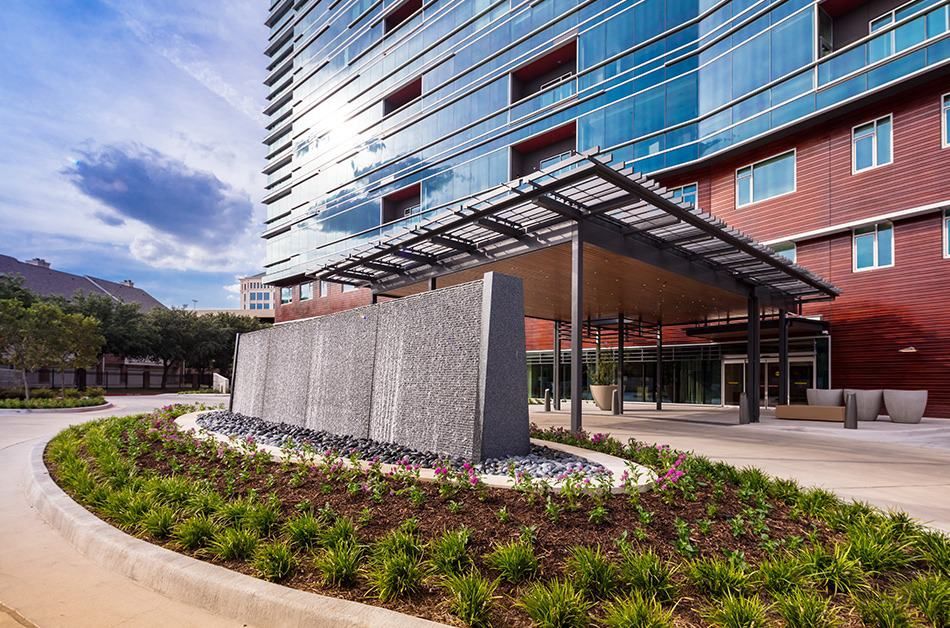 A modern building with a glass facade and landscaped exterior.