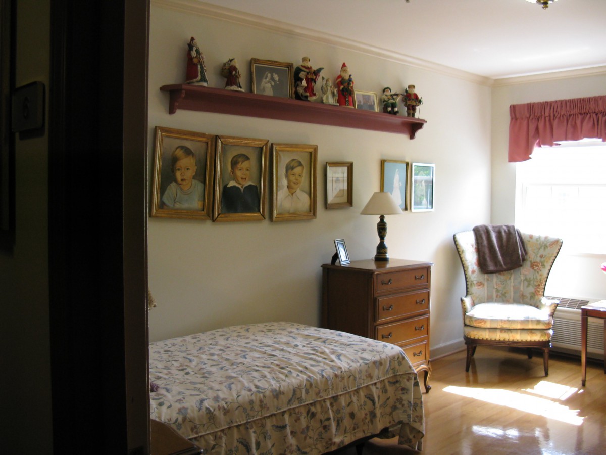A cozy bedroom with a bed, dresser, and decorative wall art.