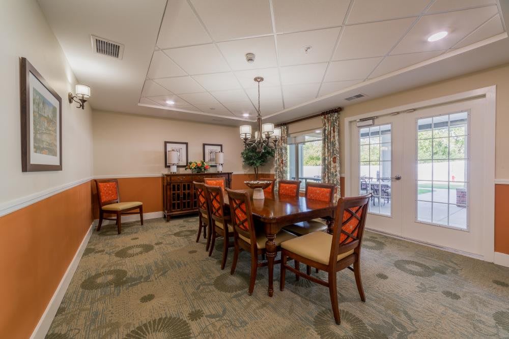 A well-decorated dining room featuring a large wooden table with upholstered chairs, elegant lighting, and warm color tones.