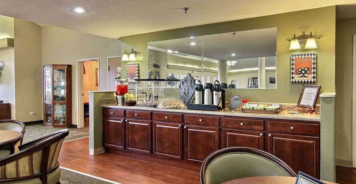 A cozy hotel breakfast area with a buffet setup including coffee and juice stations.
