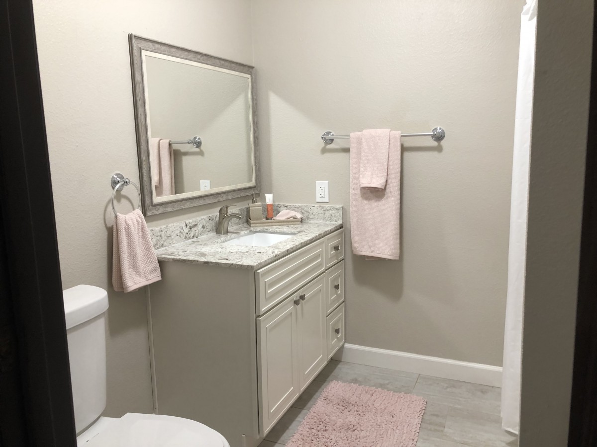 A modern bathroom with a vanity, mirror, and soft pink towels.