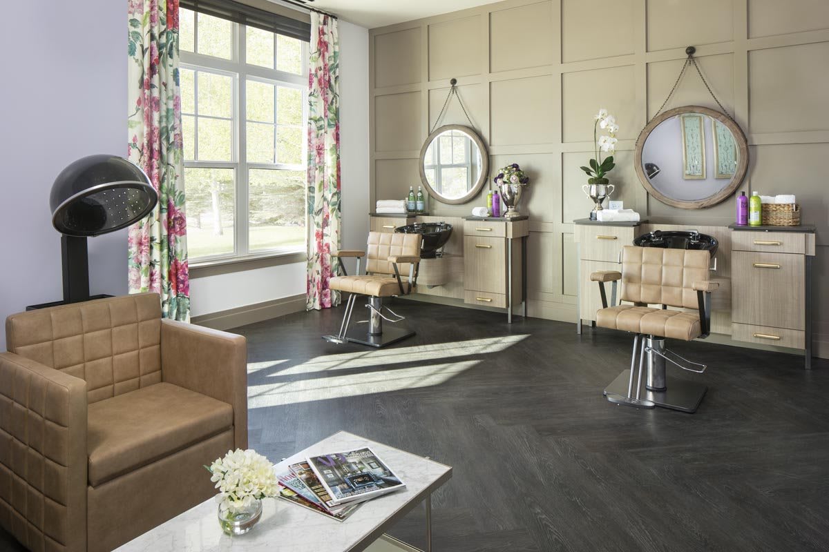 A modern hair salon interior with stylish furniture, large mirrors, and ample natural light.