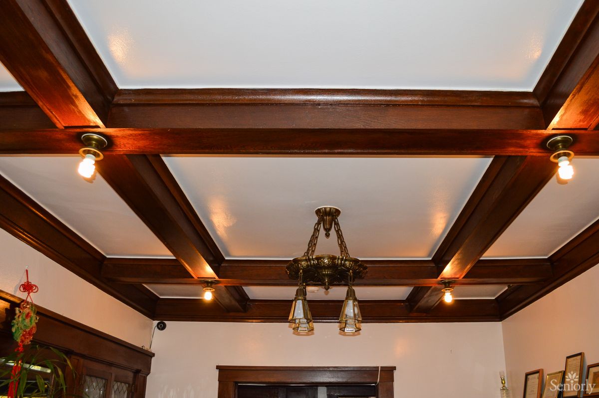 A ceiling featuring wooden beams with a central light fixture.