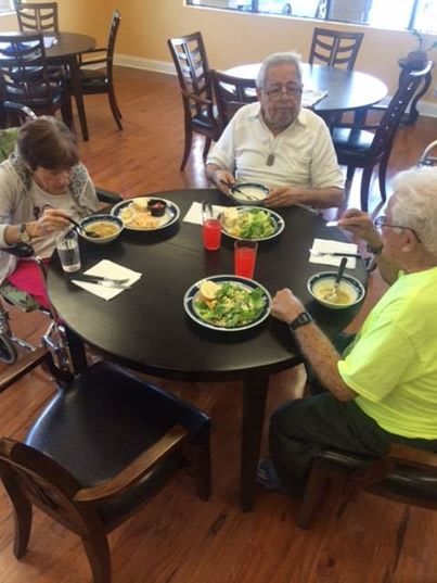 A group of seniors enjoying a meal together at a round table.