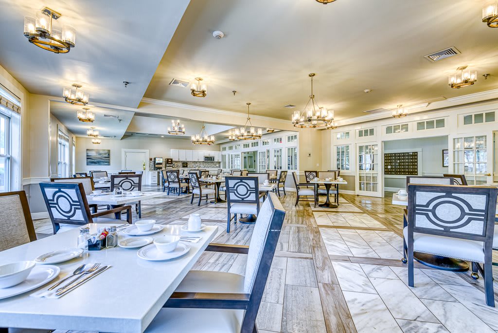 A stylish and elegant restaurant dining area with neatly arranged tables and chairs under bright chandeliers.
