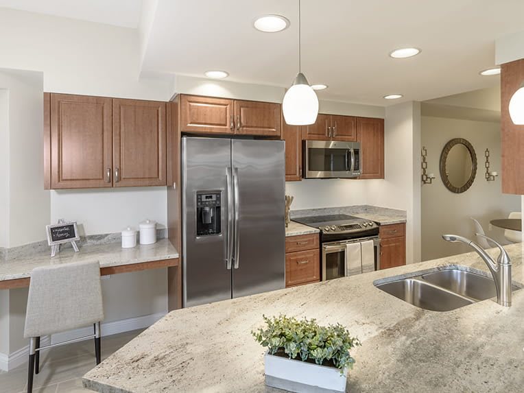 A modern kitchen featuring stainless steel appliances, wooden cabinets, and a granite countertop.