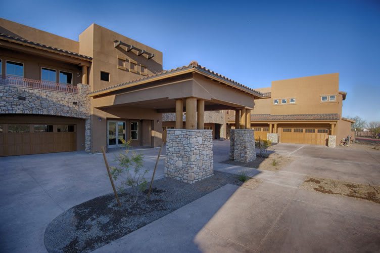 A modern building with a distinctive architectural design, featuring stone pillars and set against a desert landscape.
